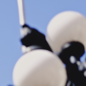 A 1:1 crop of white lamp globes against dark ironwork with halation disabled: the dark metal stays dark and edges are crisp.